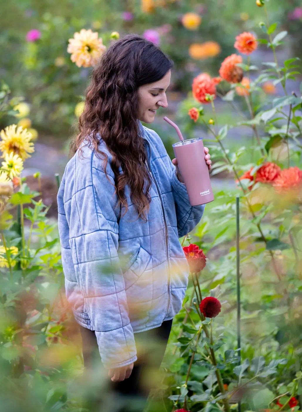 Woman holding a lavender Hydraflow tumbler among garden flowers
