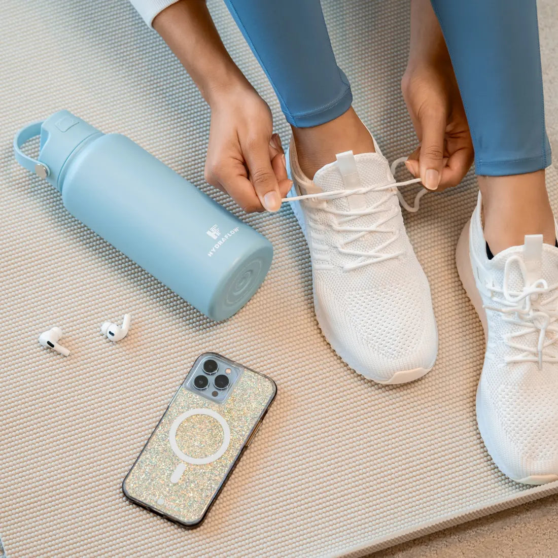 Blue Hydraflow bottle beside a woman tying her sneakers